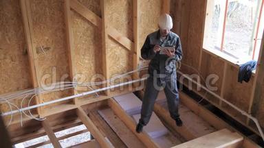 建筑师或建筑商检查半建木框架房屋的计划。 建筑工地上的建筑工人